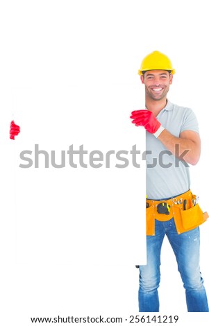 Portrait of smiling repairman holding blank billboard on white background