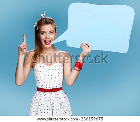 Young talkative woman showing sign speech bubble banner looking happy excited / young American pin-up girl on blue background having idea 