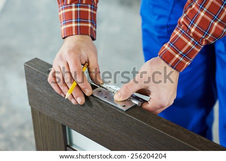Close-up carpenter process of wood door hinge installation. Royalty-Free Stock Photo #256204204