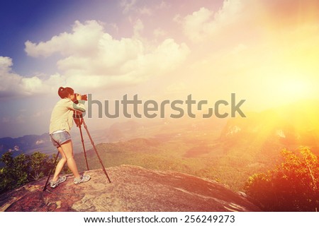 woman hiker photographer taking photo at mountain peak cliff