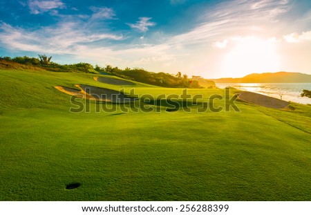 Sand bunkers at the beautiful golf course at the ocean side at sunset, sunrise time. Royalty-Free Stock Photo #256288399