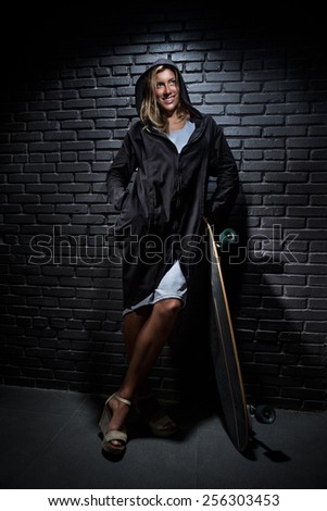 Pretty woman with skateboard against  brick background
