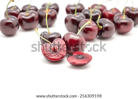 Close up of fresh reddish cherries with stem on white background