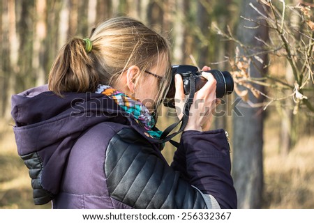 Profile portrait of nature photographer young woman, taking photos in the sunny forest, spring day