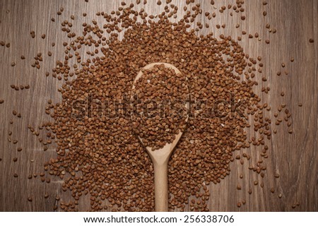 Buckwheat in black bowl on wooden background. Closeup.