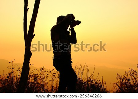 Silhouette of a young photographer during the sunset at PHU CHEEFA PARK , Chiangrai in Thailand
