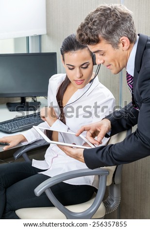 Manager using tablet computer with female customer service agent in office