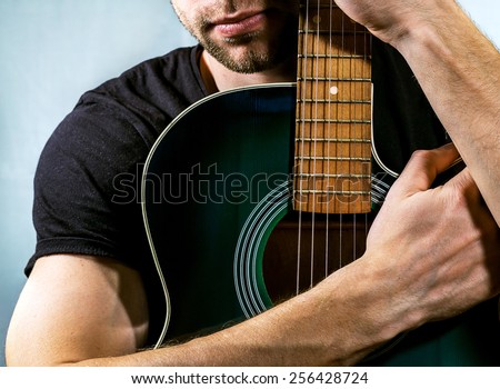 guitarist holding an acoustic guitar on a light background
