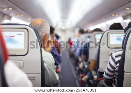 Interior of airplane with passengers on seats waiting to taik off. Royalty-Free Stock Photo #256478011