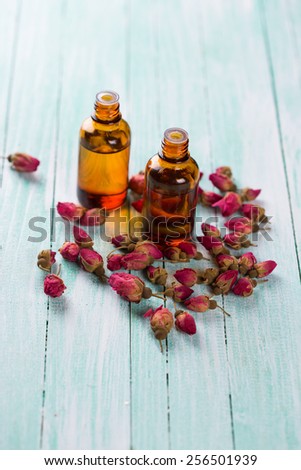 Essential aroma oil with roses  on wooden background. Selective focus.