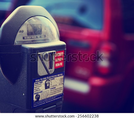 a parking meter with a car in the background on a city street downtown toned with a retro vintage instagram filter app or action effect Royalty-Free Stock Photo #256602238