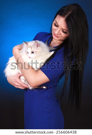 Young attractive woman with a cat over blue background