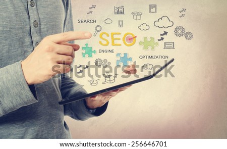 Young man pointing at SEO concept over a tablet computer