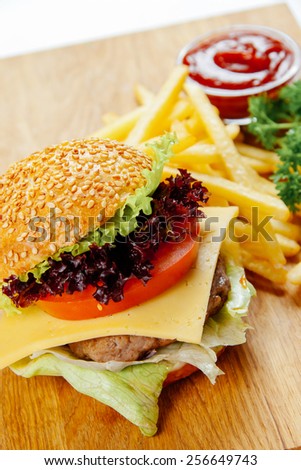 Cheeseburger with french fries on a wooden stand