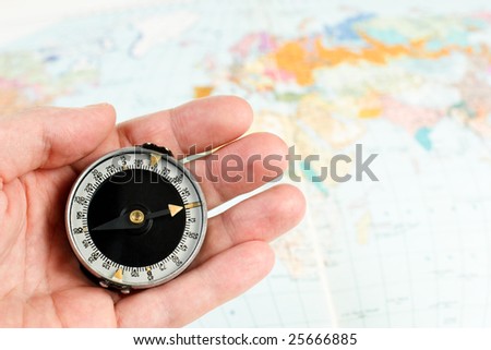 Hand holding compass with map of the world in background