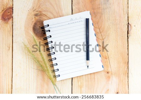 Note book and pencil on wooden background