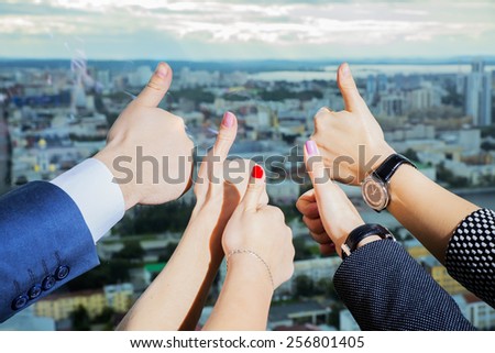 Close-up of business team holding their thumbs up against the background of the city
