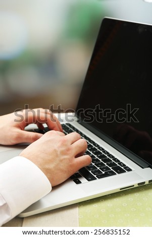 Man working on laptop on table, close-up, on bright background