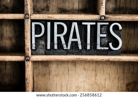 The word "PIRATES" written in vintage metal letterpress type in a wooden drawer with dividers.