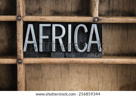 The word "AFRICA" written in vintage metal letterpress type in a wooden drawer with dividers.