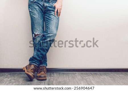 Young fashion man's legs in jeans and boots on wooden floor Royalty-Free Stock Photo #256904647