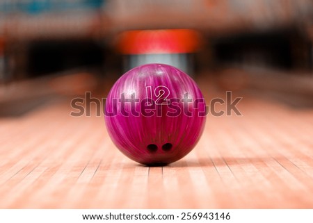Bowling in details. Closeup of lilac bowling ball lying on bowling alley