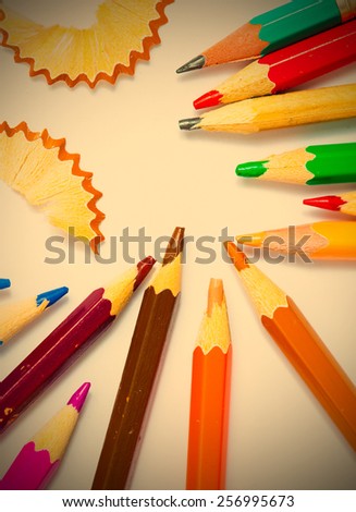 several colored pencils and shavings on white background with copy space. instagram image retro style