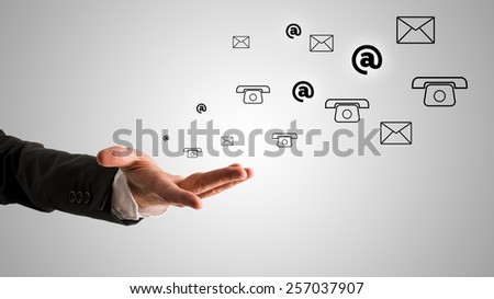 Conceptual One Open Businessman Hand with At, Telephone and Mail Symbols on Gray Gradient Background.