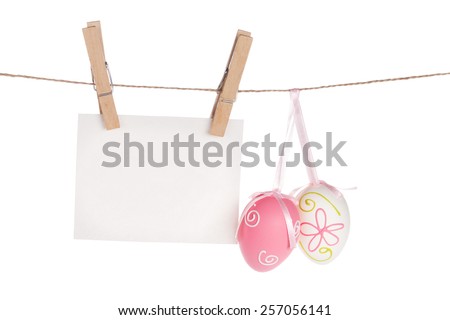Colorful easter eggs and blank photo frame hanging on rope. Isolated on white background