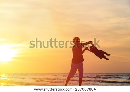 silhouettes  of father and little daughter playing at sunset
