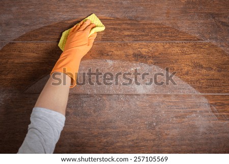 Close-up of hand cleaning wooden table with dishrag Royalty-Free Stock Photo #257105569