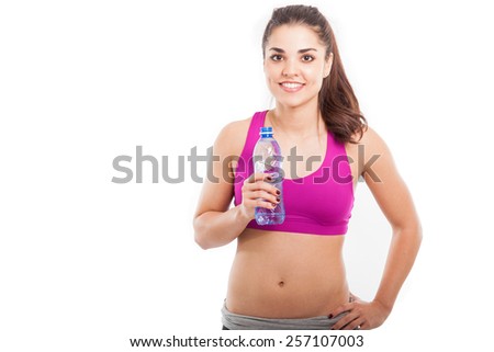 Strong and pretty Latin young woman in sporty outfit drinking water from a bottle with plenty of copy space