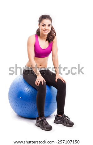 Pretty young woman in sporty outfit sitting on an exercise ball and smiling