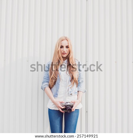 beautiful blonde woman with vintage camera on summer background wall