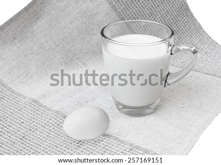 Glass mug of milk and egg on linen cloth background