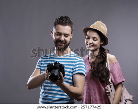 Trendy young hipster tourist couple with camera. Studio shot on gray background.
