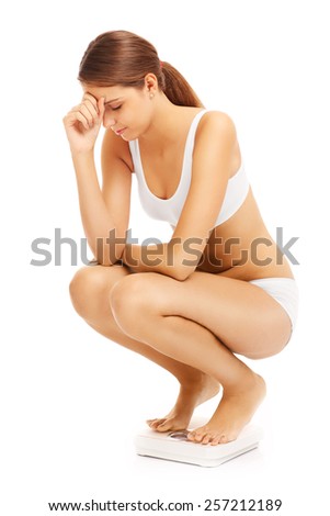 A picture of a sad woman on a bathroom scales over white background