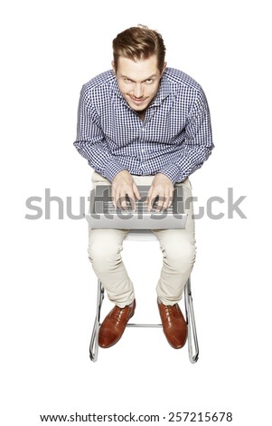 Young man working on a computer on his knees.
