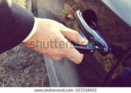 a hand holding a car's remote control pointing to the door