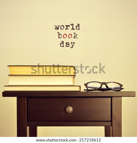 black eyeglasses and some books on a table and the sentence world book day on a beige background, with a retro effect Royalty-Free Stock Photo #257218612