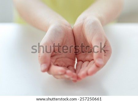 people, charity, childhood and advertisement concept - close up of child cupped hands at home