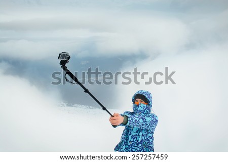 Man taking selfie using action camera at the mountains. Outdoor activities on fresh winter air