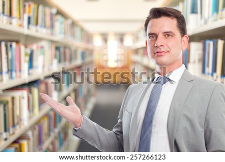 Business man with grey suit, he is offering something. Over library background