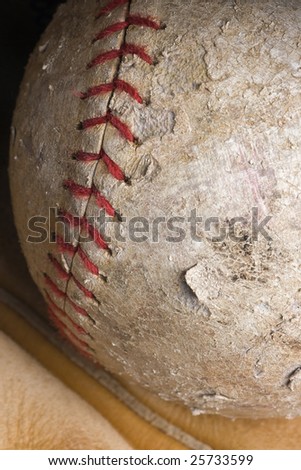well-used softball with red stitching in mitt