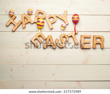 Words Happy Easter made of wooden letters decorated with colorful toy eggs as a festive Easter background composition