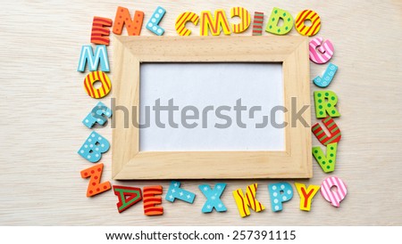 Colorful wooden alphabet letter set outside picture frame. Concept of back to school. Shot with natural light. Slightly defocused and close-up shot. Copy space.