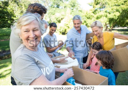 Happy volunteer family separating donations stuffs on a sunny day Royalty-Free Stock Photo #257430472