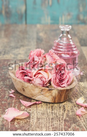 Aromatherapy rose massage oil.  Essential oil with roses on rustic wooden background. A macro photograph with  shallow depth of field. Done with a vintage retro filter