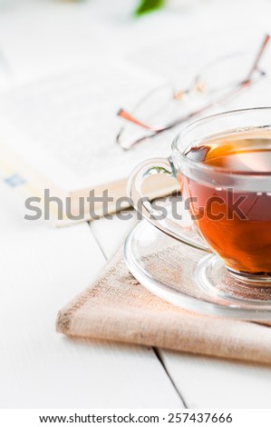 cups of tea with book on wooden table.