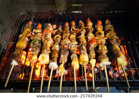 kebabs skewered with peppers and tomato sizzling over the coals of a barbecue